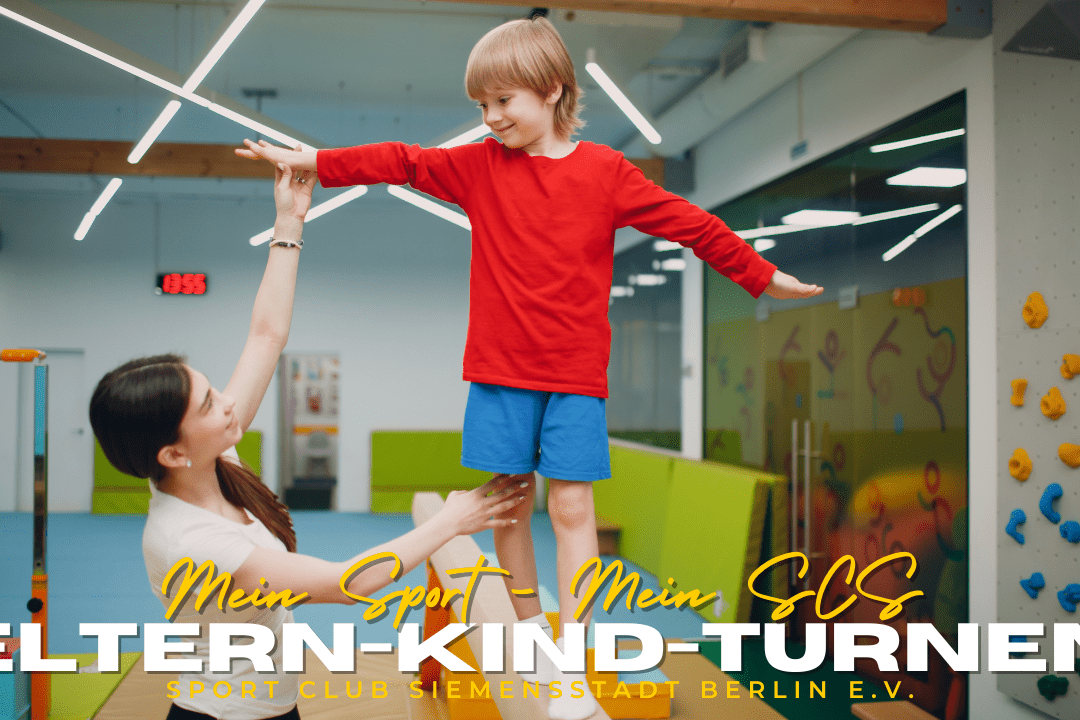Mutter hebt lächelnd ihren Sohn in rotem Shirt während des Eltern-Kind-Turnens in einem Sportclub.