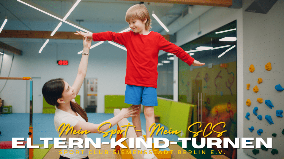 Mutter hebt lächelnd ihren Sohn in rotem Shirt während des Eltern-Kind-Turnens in einem Sportclub.