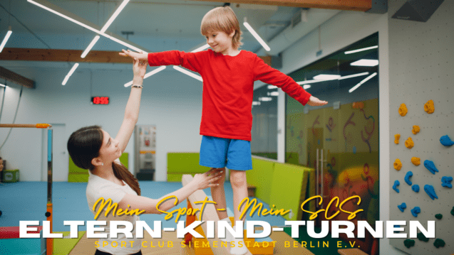 Mutter hebt lächelnd ihren Sohn in rotem Shirt während des Eltern-Kind-Turnens in einem Sportclub.