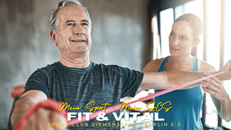 Älterer Mann an einem Fitnessgerät mit Widerstandsbändern, unterstützt von einer Trainerin in einem hellen Raum.