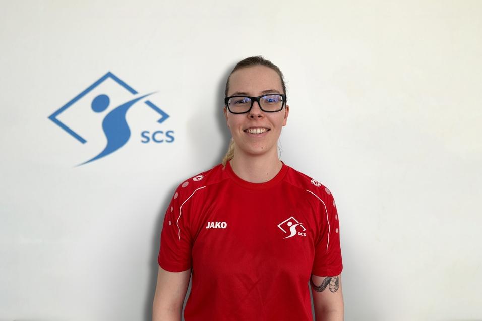 Portrait einer Person in rotem Shirt mit "JAKO"-Logo, vor einem weißen Hintergrund mit "SCS"-Logo.