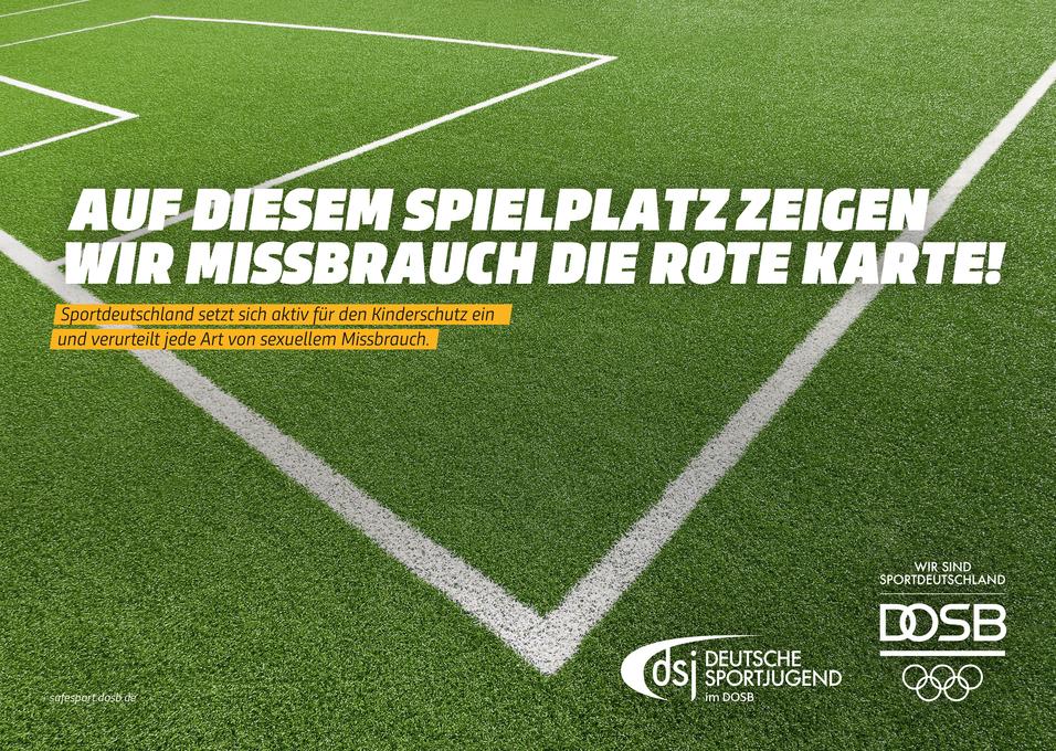 Grüner Sportplatz mit weißen Linien; Schrift: „Auf diesem Spielplatz zeigen wir Missbrauch die rote Karte!“