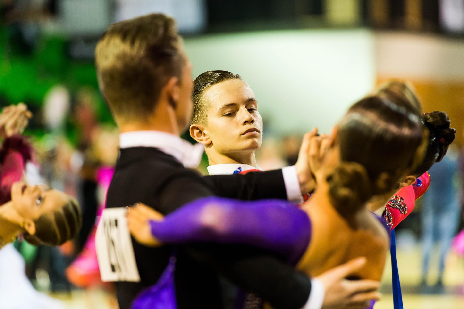 Tänzer in eleganter Kleidung während eines Wettbewerbs, fokussiert auf die Choreografie in einer Tanzhaltung.