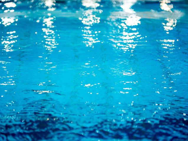 Wasseroberfläche mit Lichtreflexionen in verschiedenen Blau- und Türkistönen. Sanfte Wellenbewegungen sichtbar.