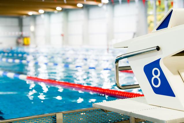 Startblock Nummer 8 an einem Schwimmbecken mit blauen Wasser und Schwimmbahnen im Hintergrund.